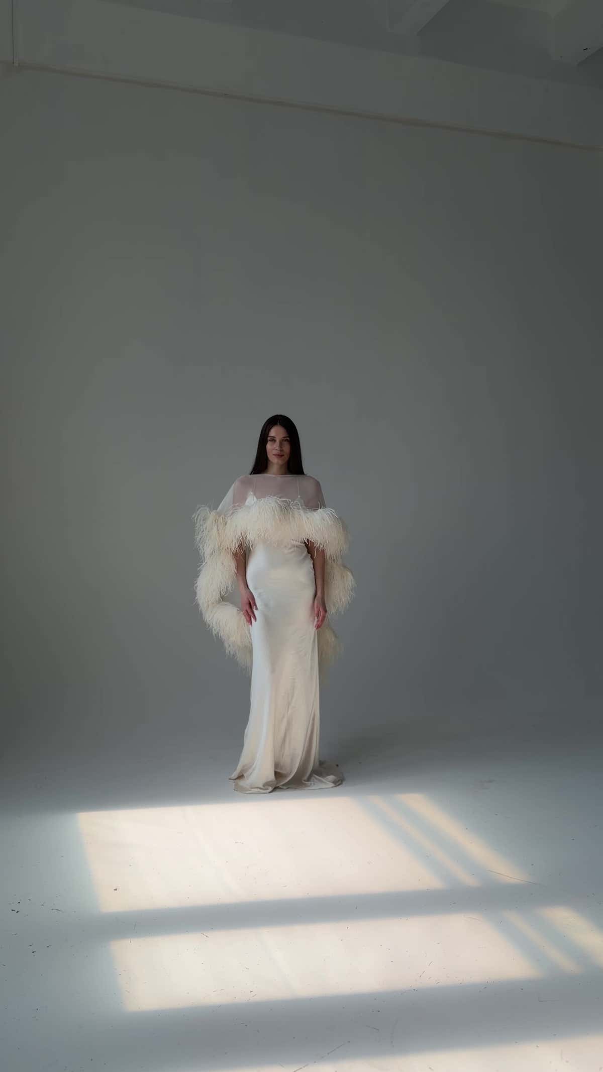 Video: Odette mermaid satin slip wedding dress with the feather cape, bride standing in a pool of studio light
