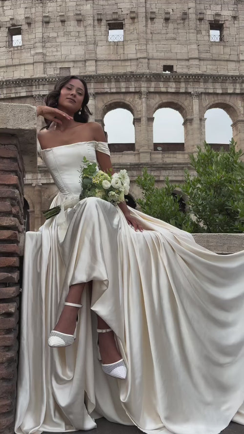 Video: Amarelle satin A-line wedding dress, bride seated on a wall with a bouquet and the skirt spread wide